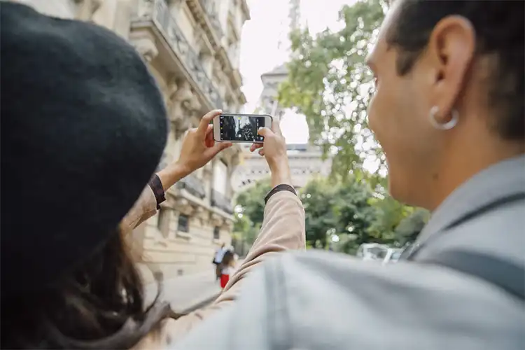 Turistas utilizam celular para fotografar a Torre Eiffel no inverno
