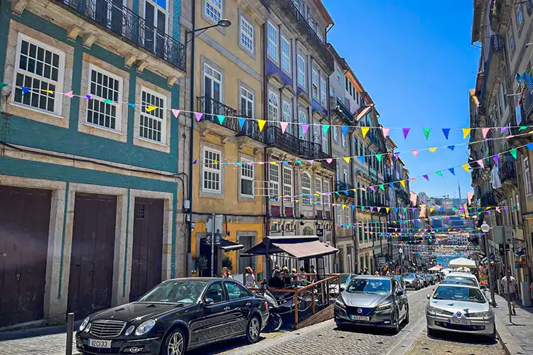 Carros circulando e outros estacionados em rua do Porto