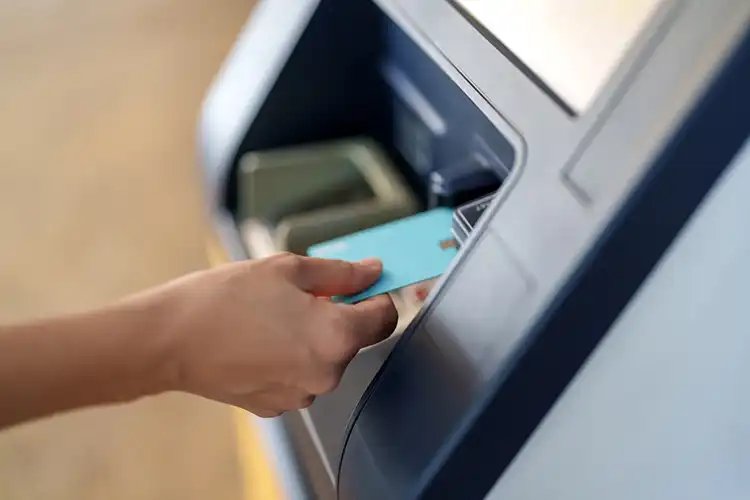 Pessoa insere cartão Visa Travel Money em ATM para sacar dinheiro