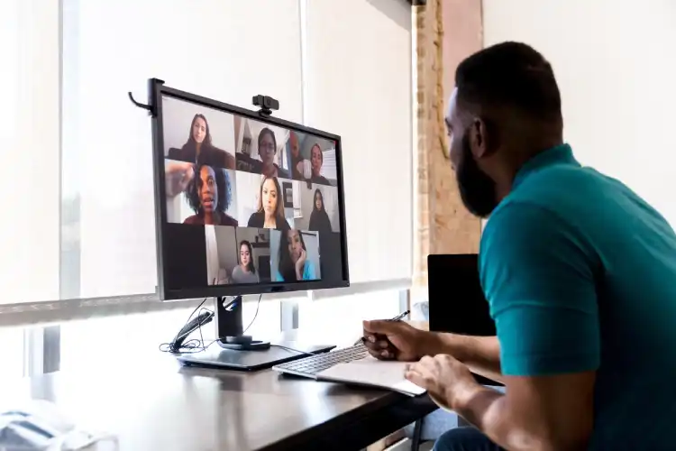 Homem conduz reunião online com grupo diverso de participantes em tela de computador