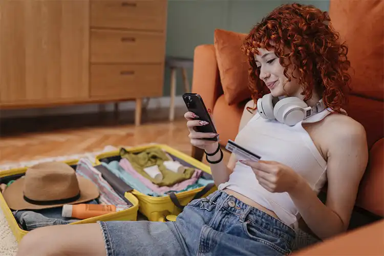 Garota utiliza smartphone e segura um cartão de débito