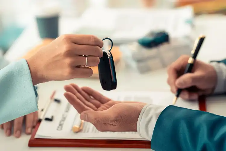 Pessoa recebe a chave de carro alugado