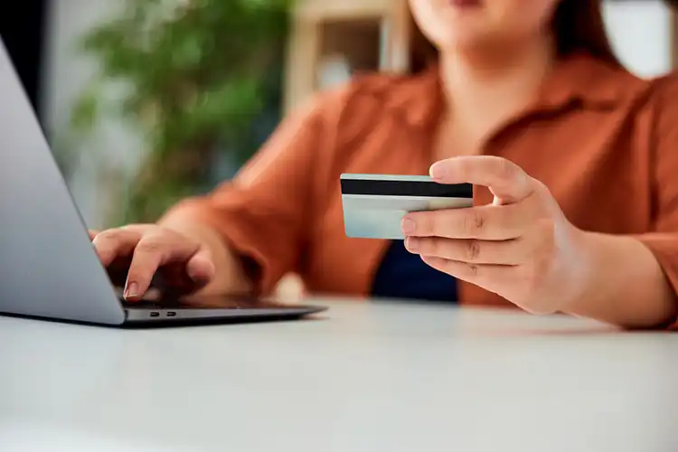 Mulher faz pagamento online com cartão de crédito no notebook