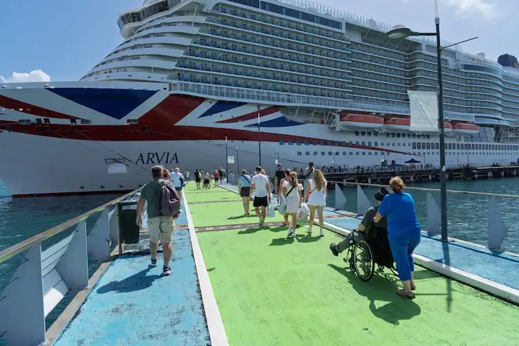 Passageiros embarcando em um navio de cruzeiro ancorado em porto tropical