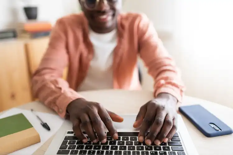 Homem com as mãos em cima de laptop