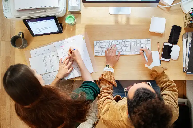 Estudantes com papéis na mesa e computador