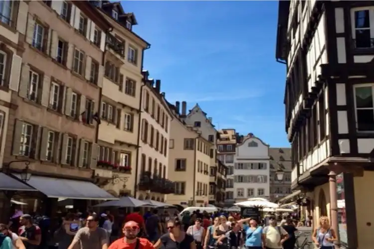 Turistas e locais passeiam pelo movimentado centro de Estrasburgo, representando nossa falta de planejamento prévio para essa viagem e os nossos diferentes jeitos de viajar