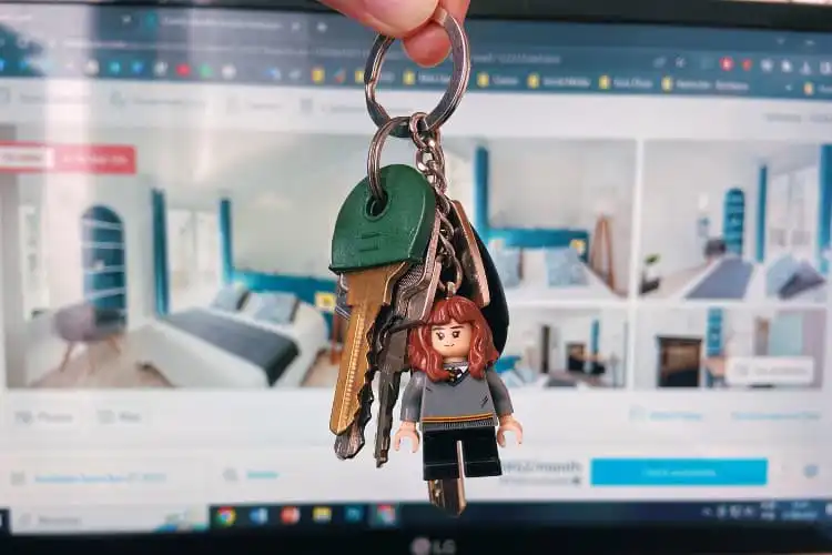 Molho de chaves com anúncio de apartamento para alugar ao fundo.