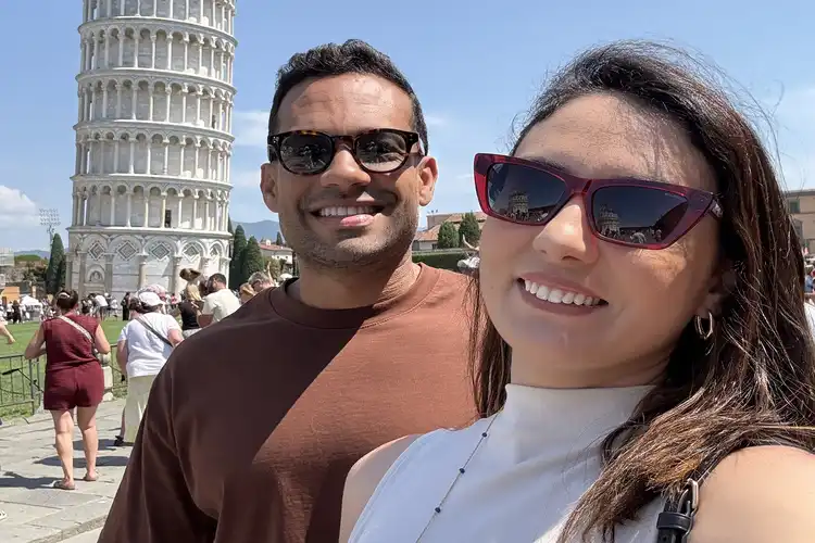Casal de brasileiros em frente à torre de Pisa, na Itália.