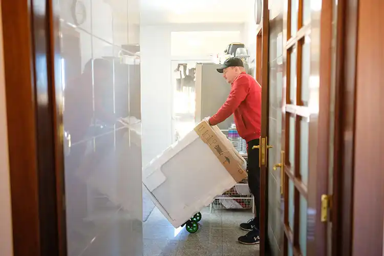 Entregador transportando máquina para cozinha usando um carrinho de mão