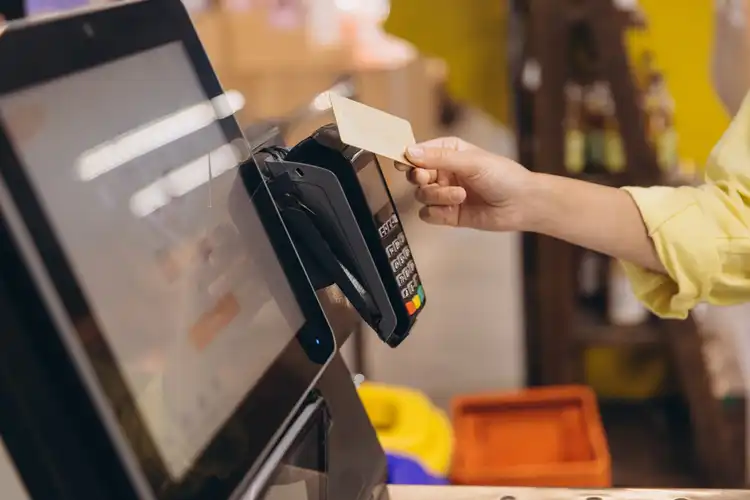 Pessoa passando o cartão para pagar conta em totem