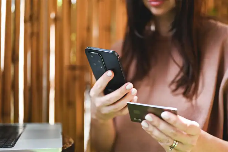 Consumidora utilizando aparelho celular e cartão Wise ou Avenue