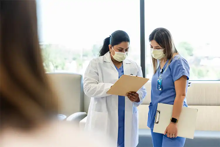 Médicas em hospital analisando documentos sobre paciente