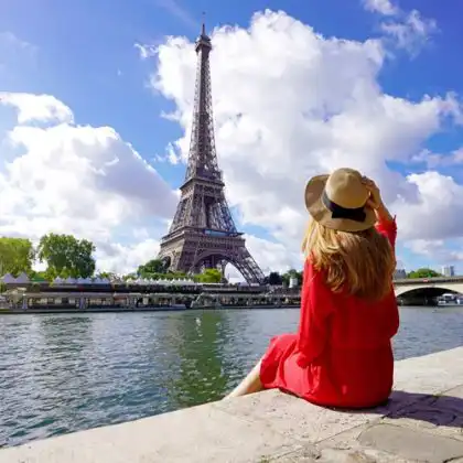 Mulher de frente para a Torre Eiffel.