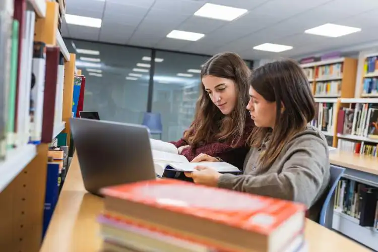 Duas estudantes em biblioteca estudando na Alemanha