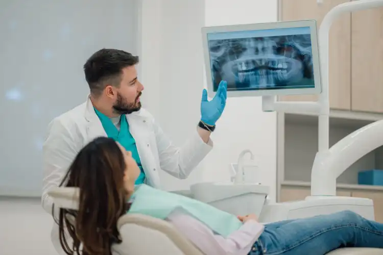Dentista apontando para Raio-x da paciente