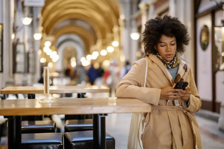 Mulher usando o celular para contratar seguro viagem já estando no exterior