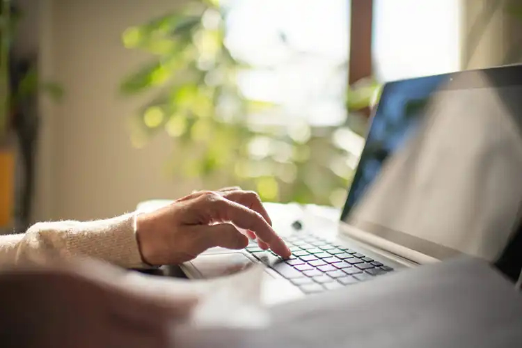 Mulher escrevendo em um notebook, procurando sobre visto para morar em Portugal aposentada