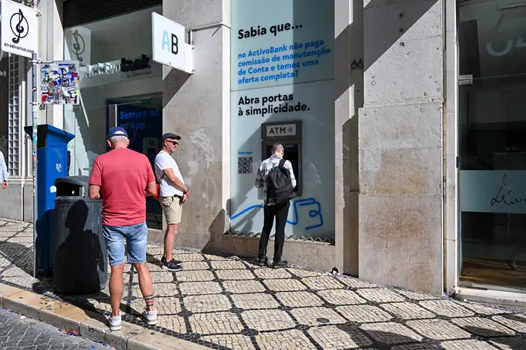 Pessoas aguardam para sacar dinheiro em caixa eletrônico do ActivoBank