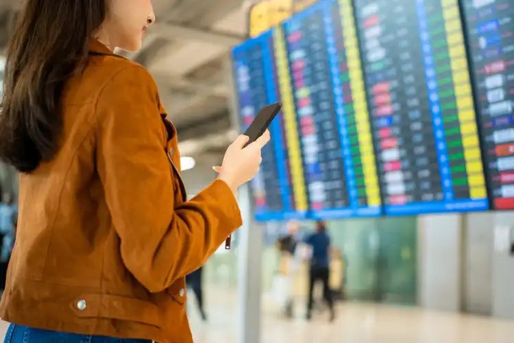 Mulher acessando a internet pelo celular no aeroporto