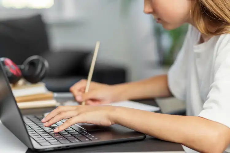Estudante escreve e usa laptop
