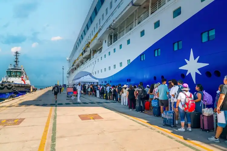 Passageiros embarcam em navio de cruzeiro em terminal portuário.