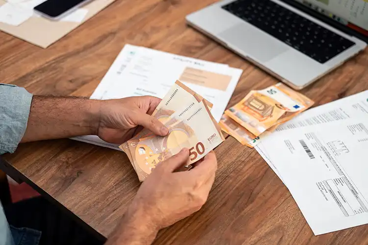Homem segura notas de euro para pagar contas em Portugal