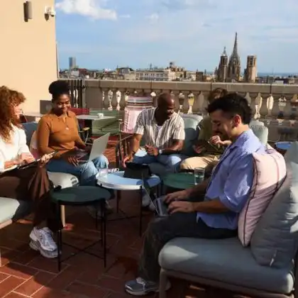 Grupo de nômades digitais conversa em terraço de prédio, em dia de sol